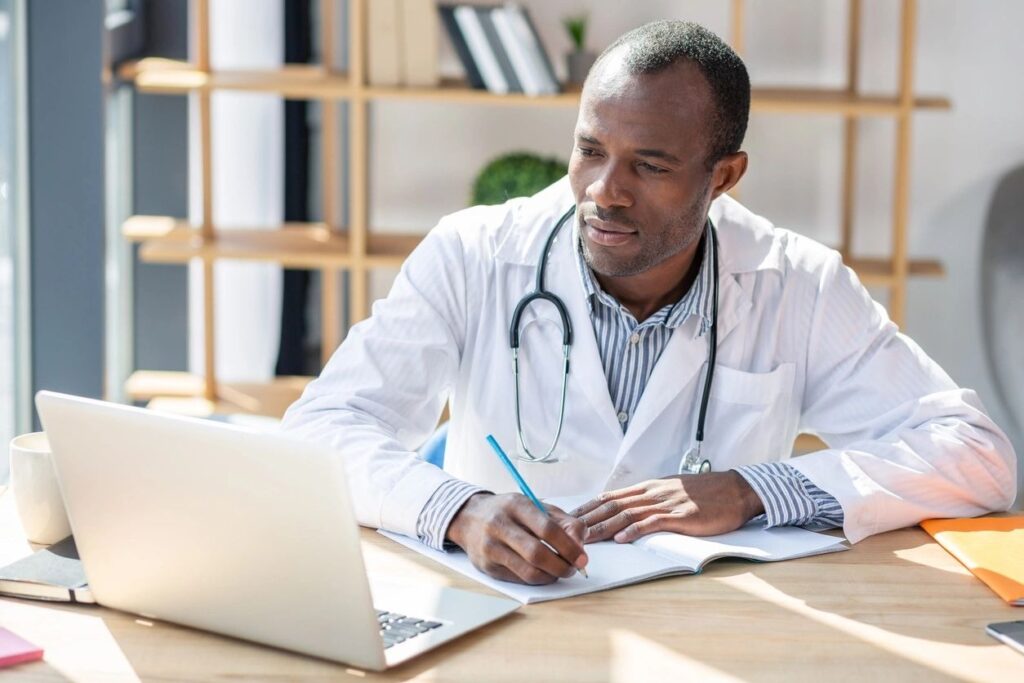 A Man in an Overcoat Sitting Infront of a Laptop